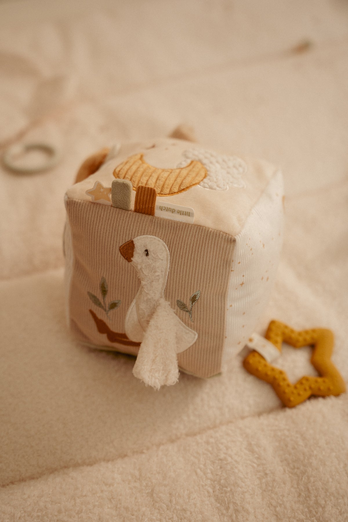 Cube d'activités bébé beige tenu par un bébé