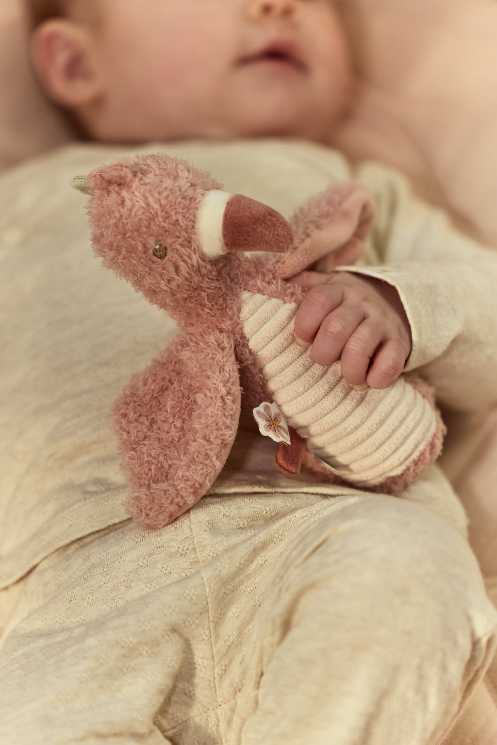 Hochet doudou flamant rose bébé tenu dans une main