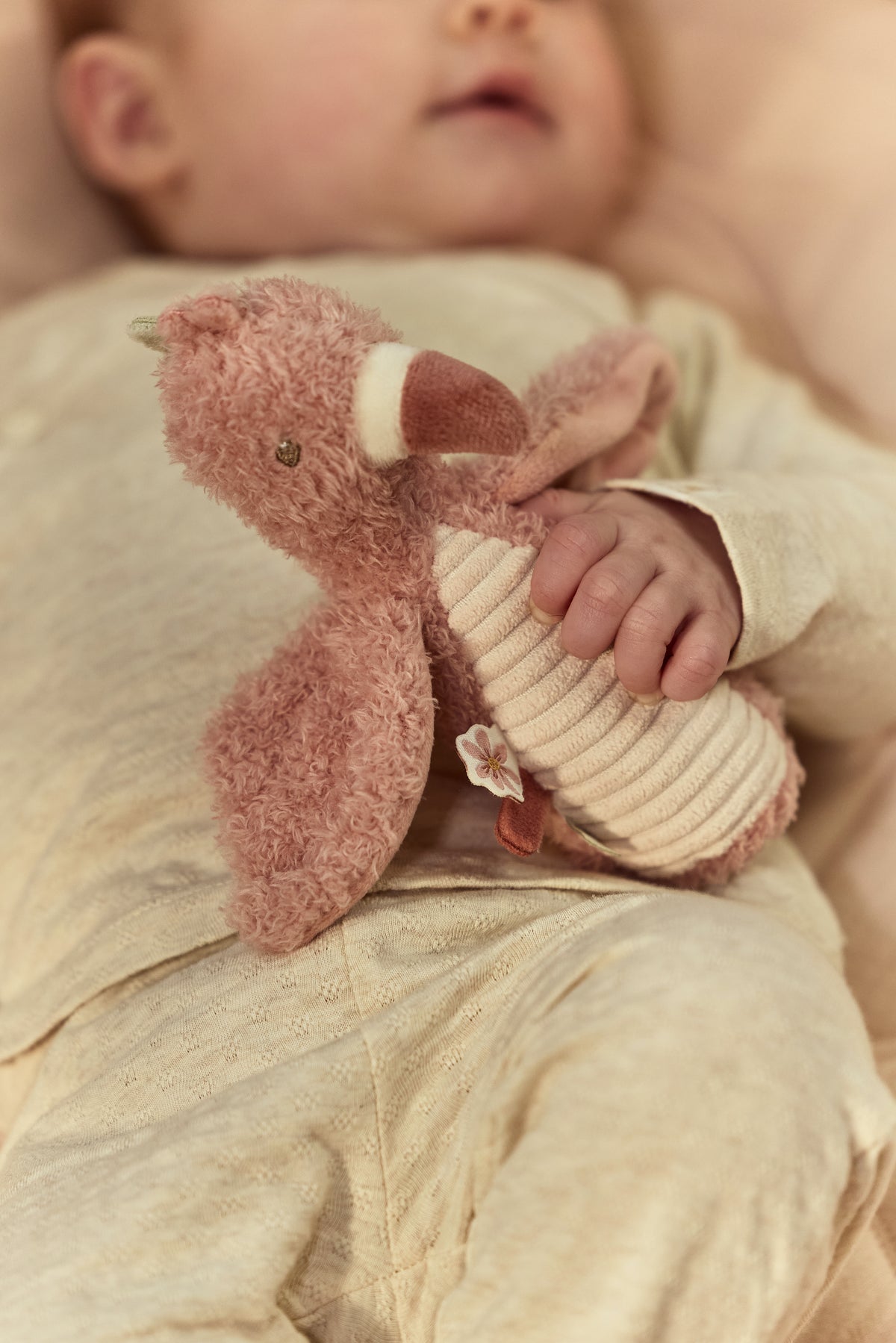 Hochet doudou flamant rose bébé tenu dans une main